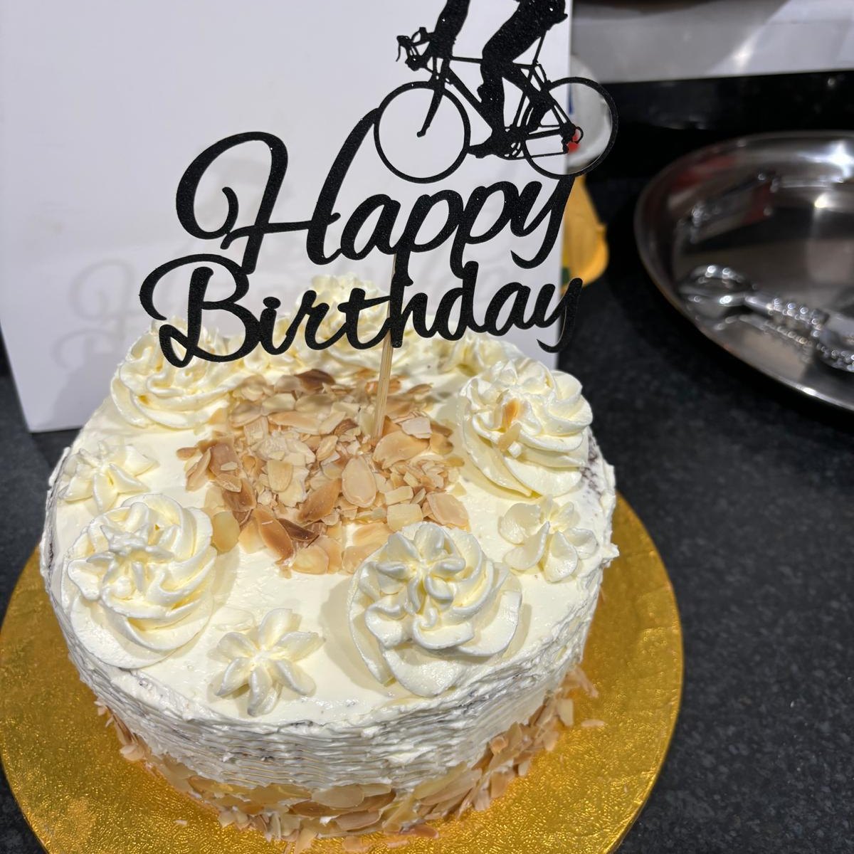 A celebration cake with piped cream and a personalised birthday topper